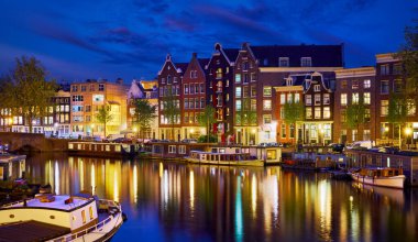 Hollanda 'nın Amsterdam şehrinde akşam vakti nehir kanalı Amstel' de