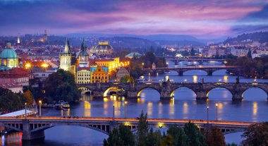 Prag Çek Cumhuriyeti. Charles Köprüsü 'nde panoramik manzara. Vltava nehri üzerindeki eski şehrin görkemli ortaçağ mimarisi. Mavi gökyüzü ve akşam aydınlatması olan gece manzarası..