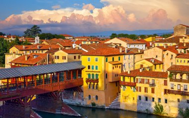 Bassano del Grappa, Veneto, İtalya. Brenta Nehri 'ndeki antik İtalyan evleri. Bassano vintage binaları ve ortaçağ ahşap köprüsü olan panoramik manzara. Bölge manzaralı gün batımı şehir manzarası.