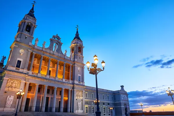 Madrid, İspanya. Santa Maria la Real de la Almudena Katedrali Plaza de la Armeria 'da. Günbatımı güneşi, çiçekler ve yeşil çalılarla ünlü bir yer. Işıklı sokak lambaları. Düşük açı görünümü.