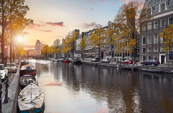 Amsterdam, Hollanda. Amstel nehrindeki ünlü evlerin panoraması, tekneli su kanalları. Eski Avrupa şehrinde popüler bir dönüm noktası ve seyahat noktası. Akşam batımı manzarası.