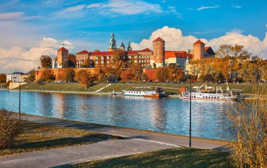 Krakow Polonya. Wawel Şatosu Wisla Nehri kıyıları. Mavi gökyüzü ve beyaz bulutlarla sonbahar günbatımı. Güneşli akşam sahnesi.
