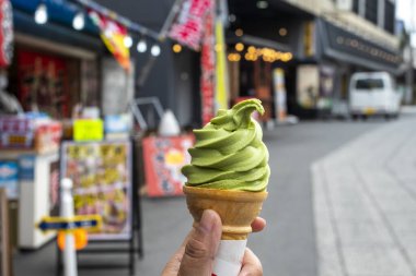 Japon turist pazarında elinde dondurma külahı yeşil çay tutan bir kızın eli.