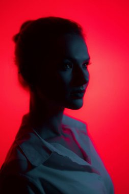 Dark woman profile portrait on red background. Lights play.