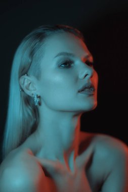 Fashion woman portrait on dark background with soft blue and red lights play on skin.