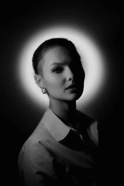 Black and white woman portrait with glowing neon circle on dark background looking to camera