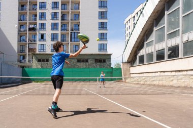 Güneşli bir günde, genç bir çocuğun tenis raketiyle tenis oynarken gölgeyle sahada durup, meçhul genç bir kızla oynadığı sahne.