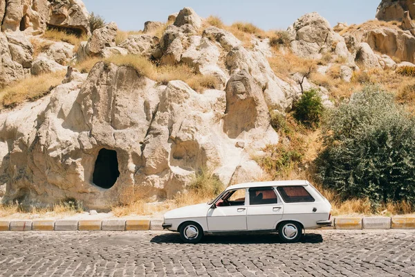 Beyaz Hatchback Arabası Asfalt Bir Yolda Büyük Kayalık Bir Tepenin Stok Resim