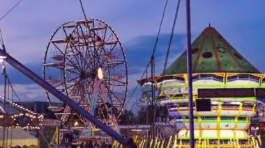 Gün batımında lunapark dönme dolabı. Birçok kulübesi olan dönme dolabın silueti gün batımında eğlence parkında sıcak turuncu gökyüzüne doğru dönüyor.