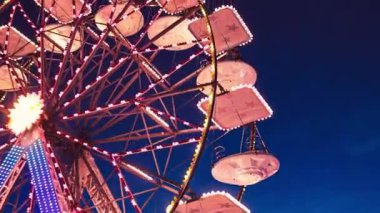 Geceleri lunapark dönme dolabı. Gece lunaparkta dönme dolap ve lunaparkta hız treni hareket ediyor..