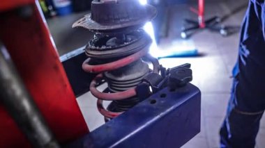 Mekanik atölyesinde araba süspansiyonu montajı. Araba süspansiyonu bakımı. Araba süspansiyonunun bakımı sırasında tamirci elleri detayı