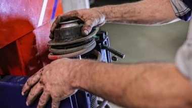 Mekanik atölyesinde araba süspansiyonu montajı. Araba süspansiyonu bakımı. Araba süspansiyonunun bakımı sırasında tamirci elleri detayı