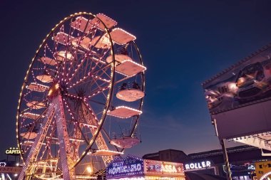 Rovigo, İtalya 25 Ekim 2022: Funfair dönme dolabı gece. Gece lunaparkta dönme dolap ve lunaparkta hız treni hareket ediyor.