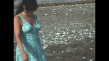 Luna, İspanya Haziran 1977: 70 'lerde elbise giymiş bir kadın deniz manzarasının yanından geçiyor