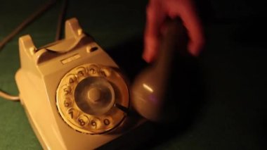 Closeup hands of man carefully places receiver of a vintage telephone in cradle