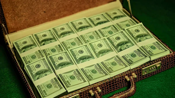 A man is seen unlocking a briefcase in a dimly lit nightclub. As he opens it, the camera reveals a stack of crisp 100-dollar notes filling the case, creating a sense of wealth and success.