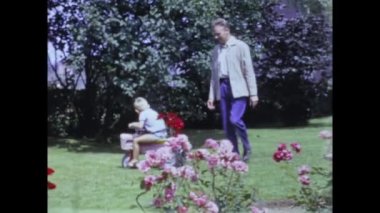 Rimini, Italy june 1975: A nostalgic video of a child playing with a pedal tractor in a garden in the 1970s.