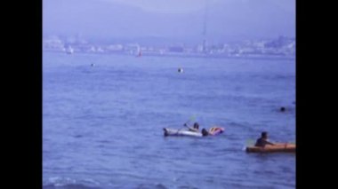 Viserba, Italy june 1975: A historic footage showing people relaxing on mattresses and canoes at the sea on vacation