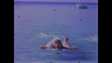 Pakostan, Hırvatistan Mayıs 1968: 70 'lerdeki aile plaj tatillerinin altın anlarını bu klasik video görüntüleriyle tekrar yaşayın. Manzaralı okyanus manzarası ve birlikte oynayan mutlu aileler.
