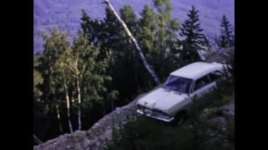 Dolomites, Italy june 1975: Historical footage of vintage cars driving on the scenic roads of the mountains in the 1970s.