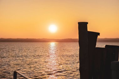 Beautiful sunset over the stunning Garda Lake in Italy, with the sun reflecting on the calm water and creating a peaceful atmosphere. Perfect for travel and nature-related projects.