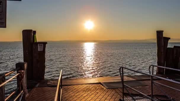 美丽的落日笼罩在意大利壮观的加尔达湖上 阳光映照在平静的水面上 营造出和平的氛围 非常适合旅行和与自然有关的项目 — 图库视频影像