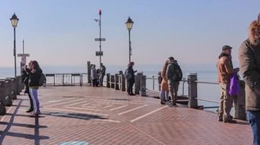 Sirmione, Italy 15 February 2023: A photo capturing the charm of Sirmione's pier, as tourists take a leisurely stroll and enjoy the stunning views of Lake Garda in Italy