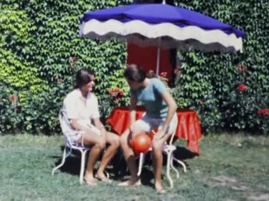 Paris, Fransa Haziran 1970: Günlük hayatın koşuşturmasına ve koşuşturmasına bir ara verin ve 70 'lerde güzel bir bahçenin huzur içinde güneşlenen iki genç kadının bu sakin videosuyla biraz dinlenin.
