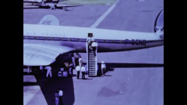 1970年 昭和45年 1970年代に飛行機から降り立った乗客のヴィンテージ映像とともにパリへ戻る スタイリッシュな服装と空港の喧騒を見てください レトロをテーマにしたプロジェクトに最適 — ストック動画