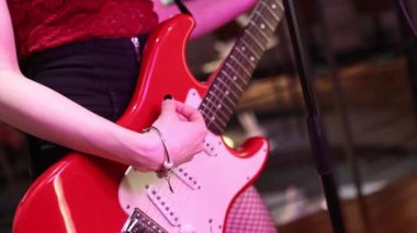 Gitar çalan, tellere ve parmaklara odaklanan bir kızın yakın plan fotoğrafı..