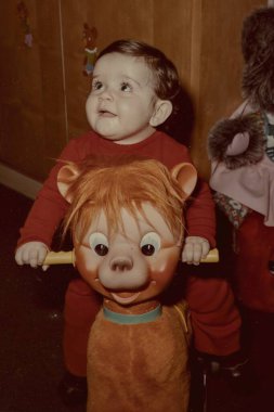 Milan, İtalya Mart 1975: Sevimli çocuk 70 'lerde neşe ve heyecanla ahşap bir sallanan ata biniyor