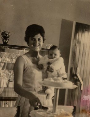 Roma, İtalya 1951: Bebeğini kucağında tutan bir annenin, 1950 'lerin nostaljik ortamında bir pasta keserken, sevgi dolu aile anılarını kutlaması..