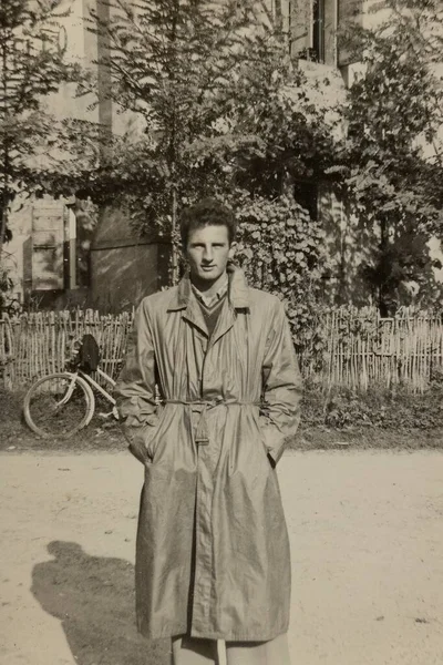 ローマ イタリア1951年5月 長いコートを着たスタイリッシュな若い男と草の上に座っている美しい女の子 ヴィンテージ1950年代の美学を呼び起こします — ストック写真
