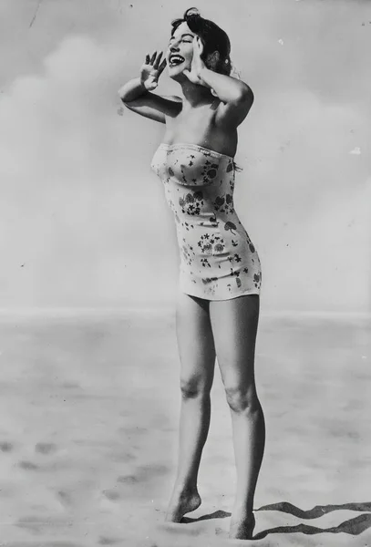 Roma, İtalya 1951: Çekici genç bir kadın kumlu bir plajda uzanırken eski moda bir mini elbiseyle kıvrımlarını sergiliyor.