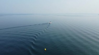 Yüksek açılı bir çekim Garda Gölü 'nün turkuaz sularından geçen bir sürat teknesini yakalar..