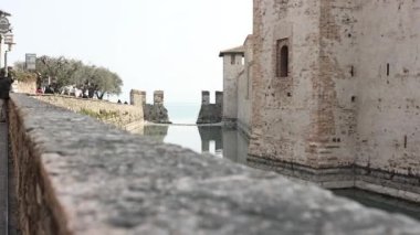 Sirmione, İtalya 11 Nisan 2023: Sirmione 'de büyüleyici küçük bir sahil görkemli kale tarafından gözden kaçırılır ve resim gibi bir İtalyan sahnesi oluşturulur..