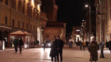 Ferrara, İtalya, 11 Nisan 2023: Genç bir çift, Ferrara 'nın tarihi merkezinin canlı caddelerinde gece boyunca yürüyor, şehrin canlı atmosferiyle ve diğer insanların akşamlarının tadını çıkararak..