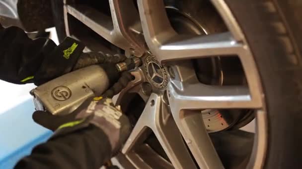ミラノ イタリア2023年4月11日 ガレージ内の車の車輪のラグナットを引き締めるために空気圧銃を使用したプロの整備士 — ストック動画