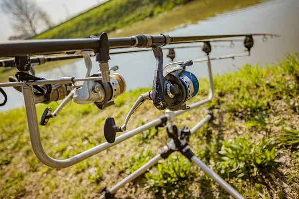 stock image A set of fishing rods and equipment for carp fishing leaning on a tripod on the riverbank.