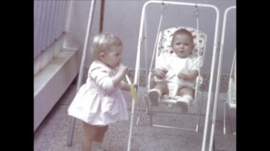 Paris, Fransa Haziran 1958: Arka bahçede açık havada salıncaktan keyif alan iki çocuğun yürek ısıtan bir videosu.