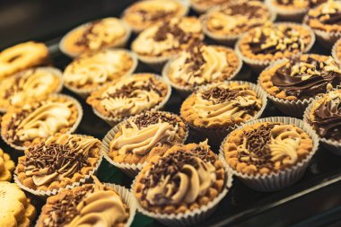 Fırın vitrinindeki çeşitli tatlıların ve pastaların renkli bir fotoğrafı. Yemek, fırın ve tatlı teması için mükemmel..