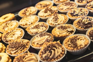 Fırın vitrinindeki çeşitli tatlıların ve pastaların renkli bir fotoğrafı. Yemek, fırın ve tatlı teması için mükemmel..