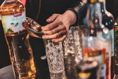 Yetenekli bir baristanın ellerinin, yaratıcı ve lezzetli bir kokteyl hazırlarken yakın plan görüntüsü..