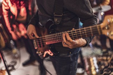 Bas gitar çalan bir basçının ellerinin yakın plan çekimi, telleri koparan ve tıngırdatan parmaklar..