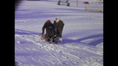 Chicago, ABD Haziran 1969: Karlı bir günde çocukların geleneksel kızaklarıyla 1960 'larda tipik bir Amerikan evinin ön bahçesinde eğlendikleri klasik görüntüler.