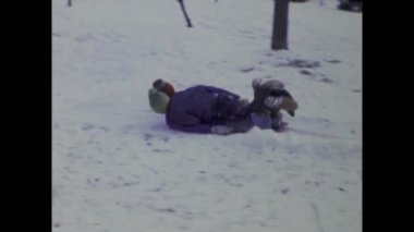 Chicago, ABD Haziran 1969: Karlı bir günde çocukların geleneksel kızaklarıyla 1960 'larda tipik bir Amerikan evinin ön bahçesinde eğlendikleri klasik görüntüler.