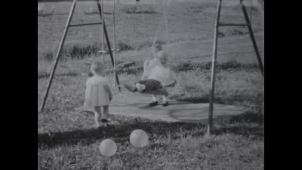1969年6月 60年代のヴィンテージ家族のビデオで庭でスイングを楽しんでいる子供たちを見るのを楽しむ — ストック動画