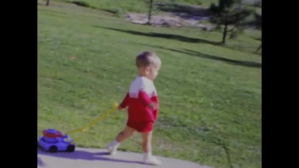 美国城市湖 1969年6月 快乐的孩子喜欢假装在后院用玩具割草机割草 怀旧和好玩的项目的完美镜头 — 图库视频影像