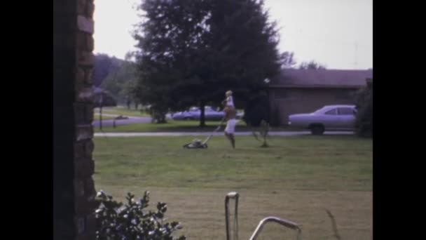 1969年6月 美国城市湖 1960年代 一位父亲背着孩子在草坪上割草的感人镜头 — 图库视频影像