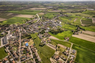 Captivating aerial perspective of a quaint village nestled amidst the lush, green Po Valley farmlands in Italy clipart